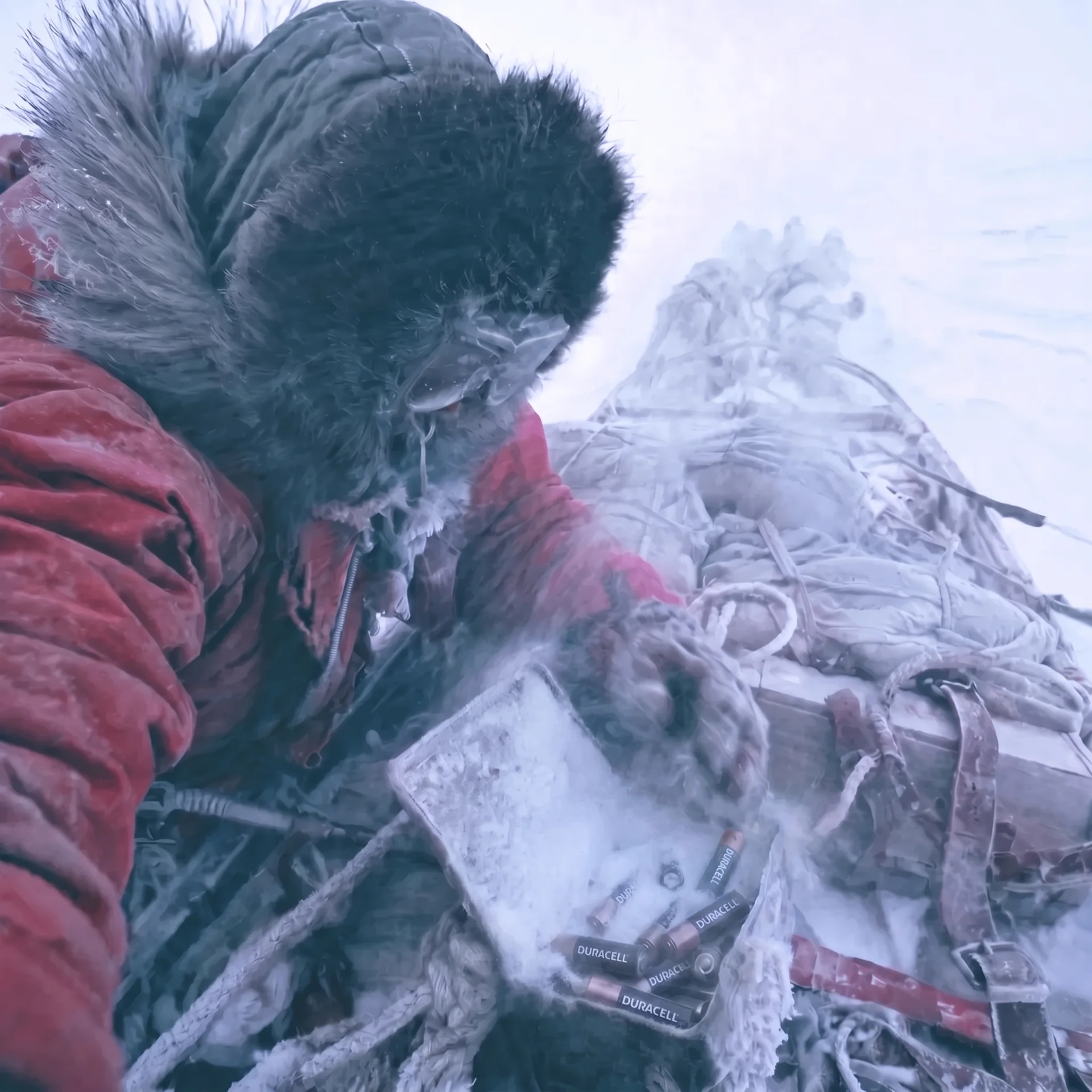 An Arctic explorer bent over a frozen sled, Duracell batteries in the snow