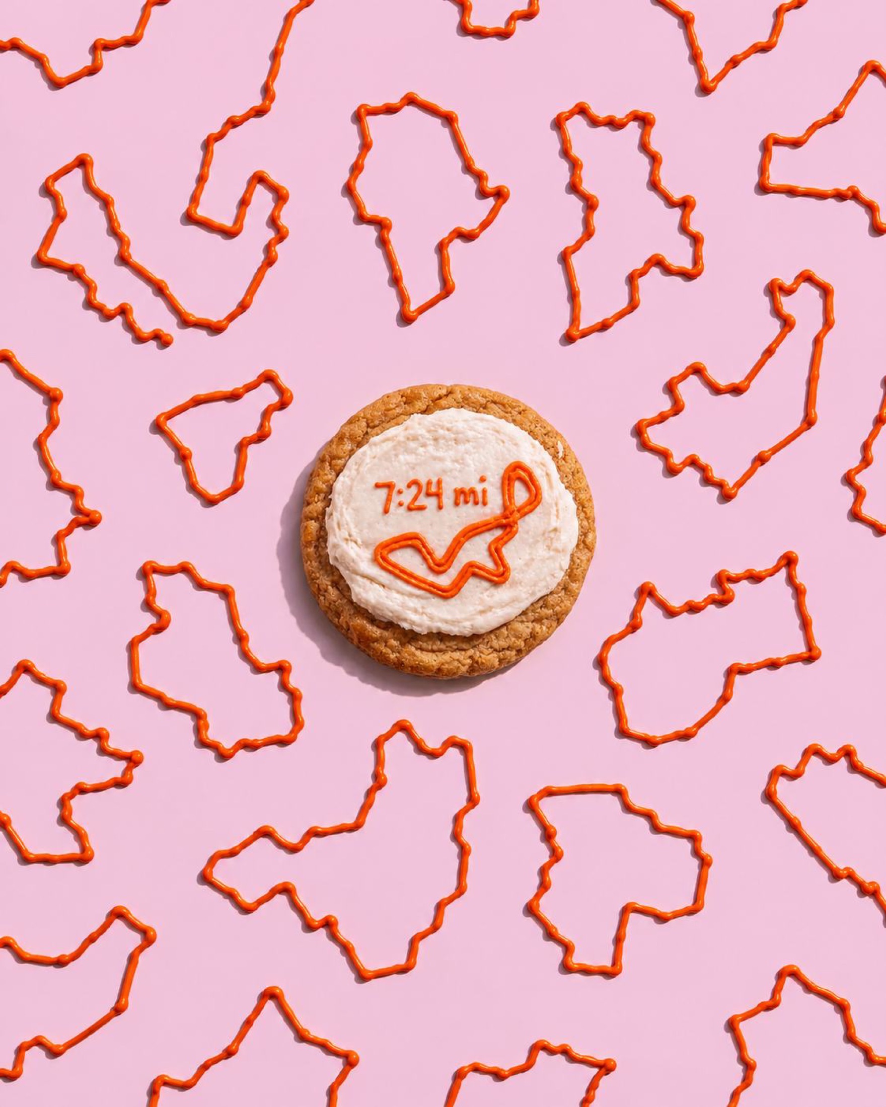 A cookie iced with a running route on a pink pattern of route outlines