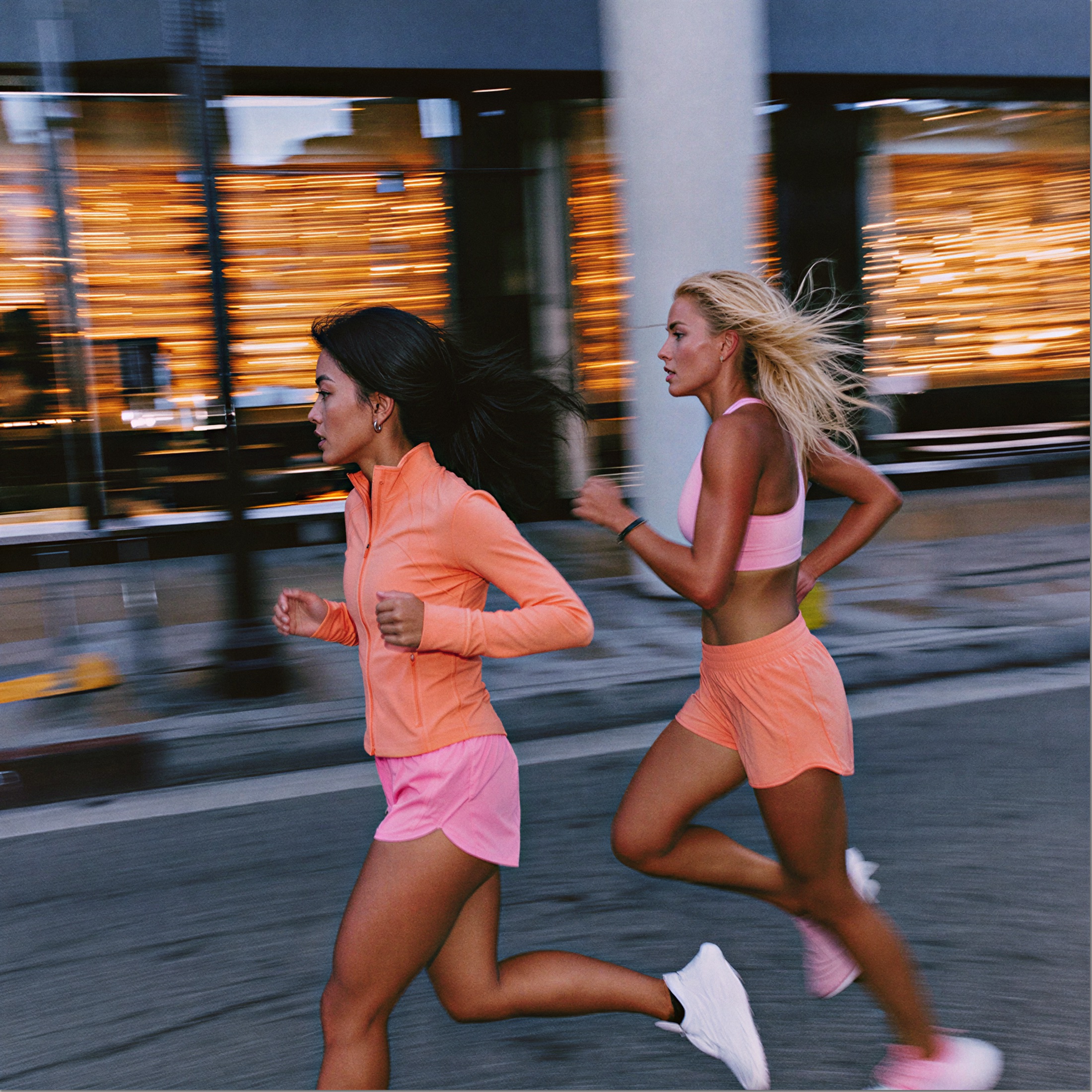 Two women running past a shopfront in pink running gear